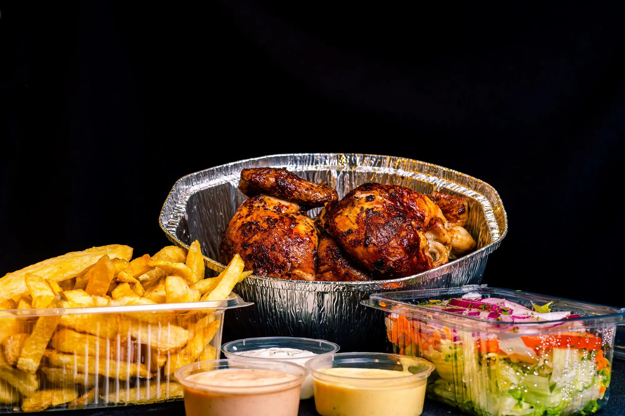Quart de poulet avec frites, salade et sauces, prêt pour emporter