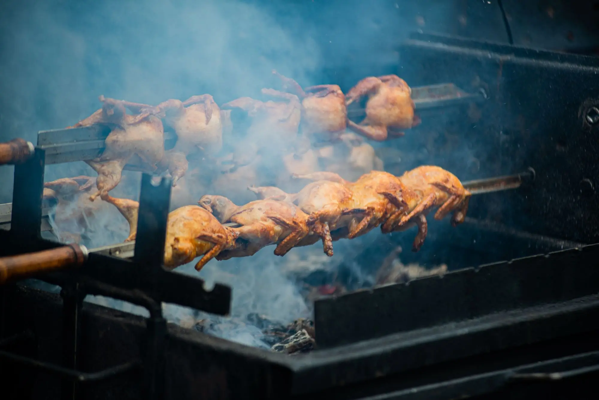 Poulets sur la broche dans la fumée des braises