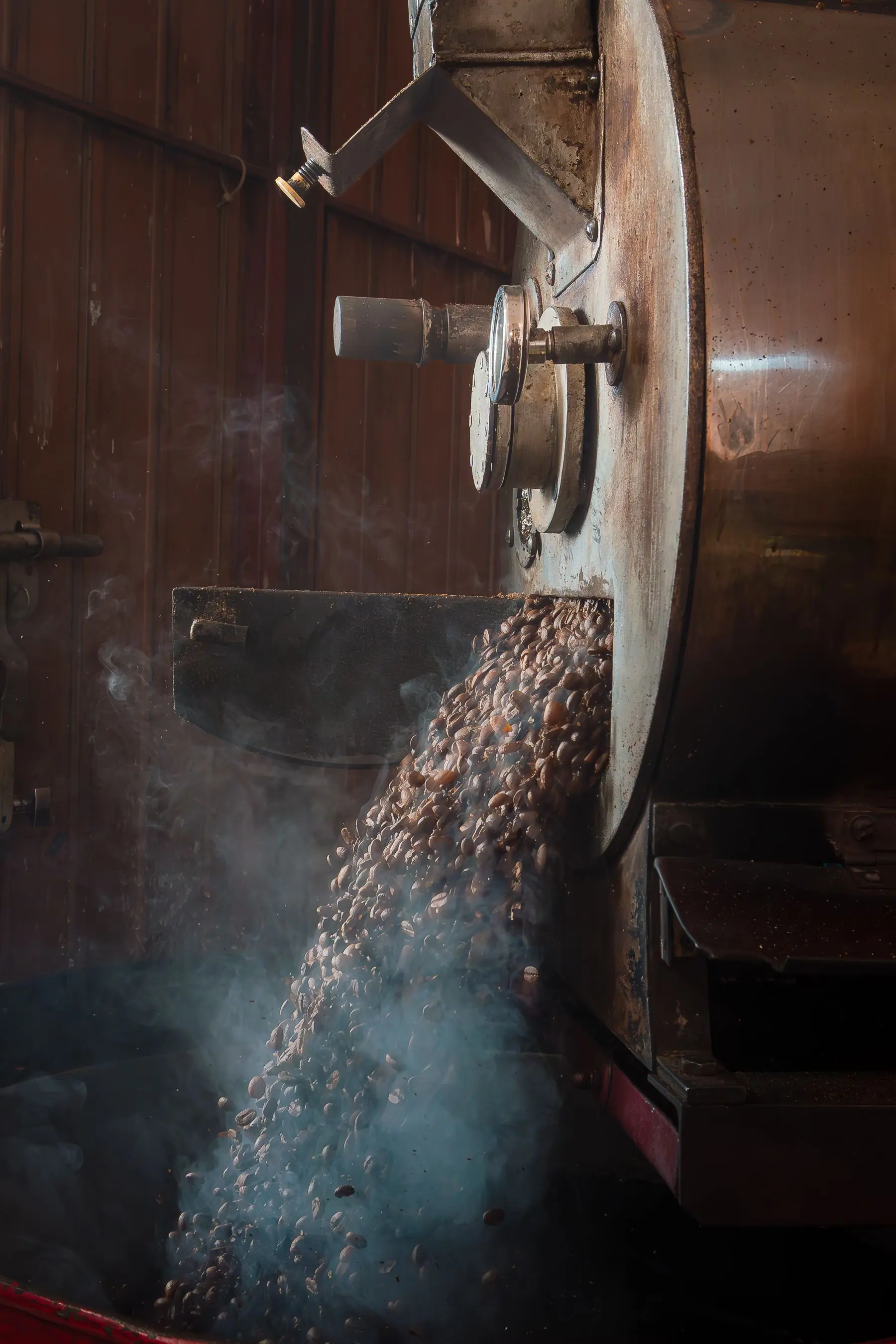 Grains de café qui sortent du torréfacteur dans un nuage de vapeur