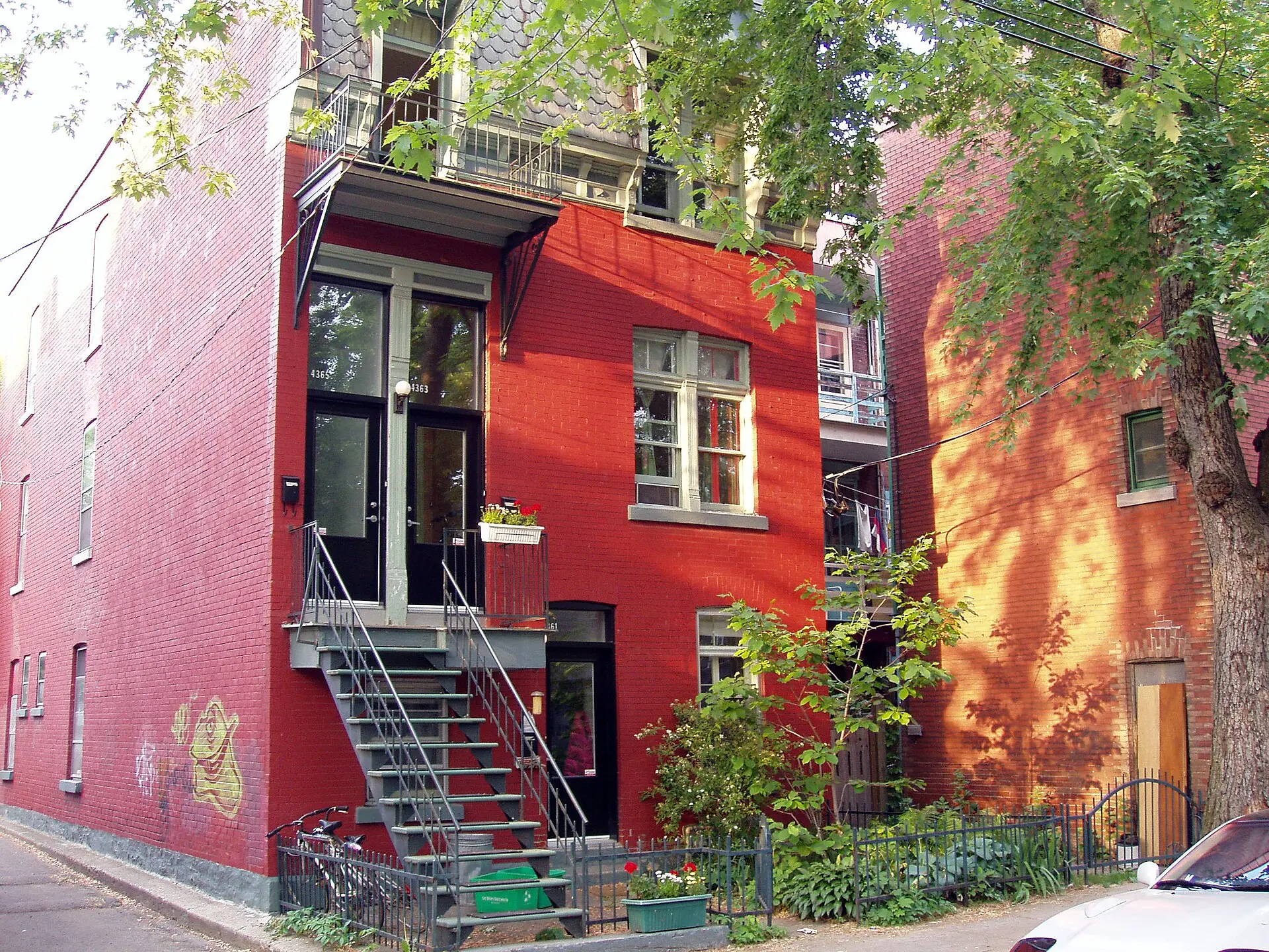 Duplex de brique rouge avec escalier extérieur, typique de Montréal