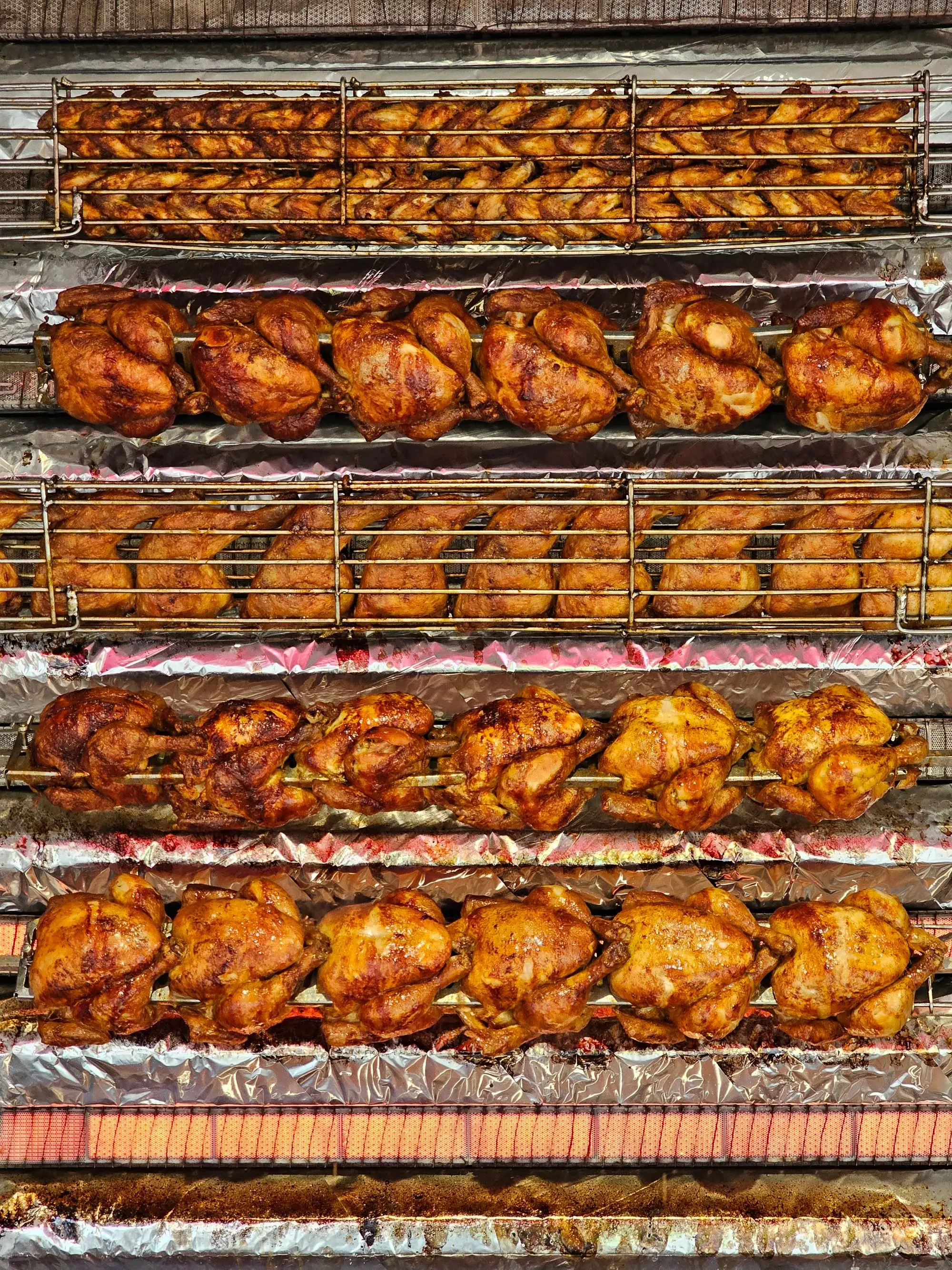 Rangées de poulets dorés sur les broches de la rôtissoire