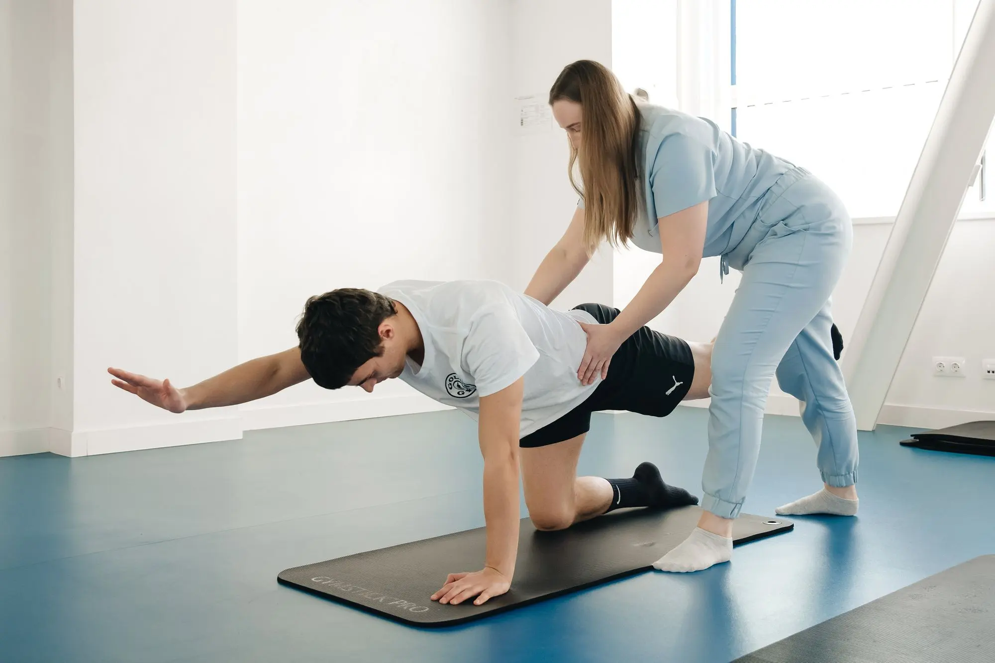 Patient en exercice sur un tapis, guidé par une physiothérapeute